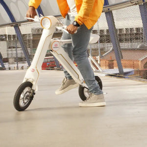 A commuter riding the white Cruzaa E-Scooter Pro across a modern city bridge.