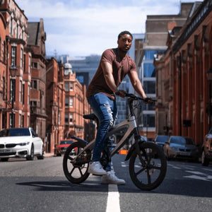 A man riding the Cruzaa electric bike through a city street, showcasing the unique frame design and urban commuter style.