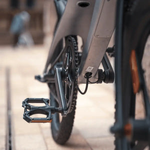 Close-up rear angle of the Cruzaa e-bike drivetrain, showing the sturdy pedals, chainring, and frame construction.
