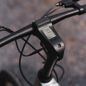 Close-up of the integrated digital display built into the handlebar stem of the Cruzaa e-bike, showing speed, battery life, and mileage.