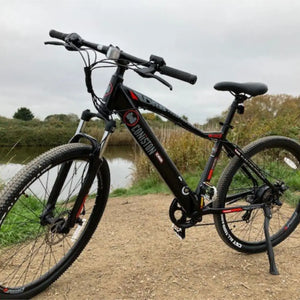 The Dallingridge Coniston electric mountain bike parked on a dirt trail next to a canal, demonstrating its off-road capabilities.