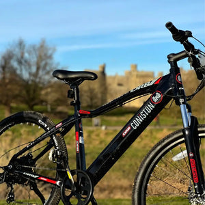 Angled side view of the Dallingridge Coniston electric mountain bike highlighting the integrated frame battery and model branding with a castle backdrop.