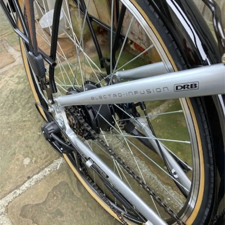 Close-up of the rear wheel showing the 250W hub motor, Shimano derailleur gears, and "Electro-Infusion" branding on the silver chainstay.