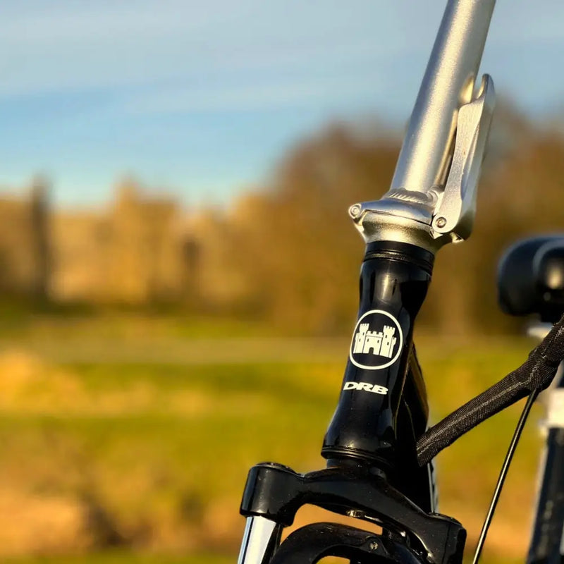 Close-up of the Dallingridge Oxford's folding handlebar stem and silver locking latch mechanism with the DRB headtube logo.