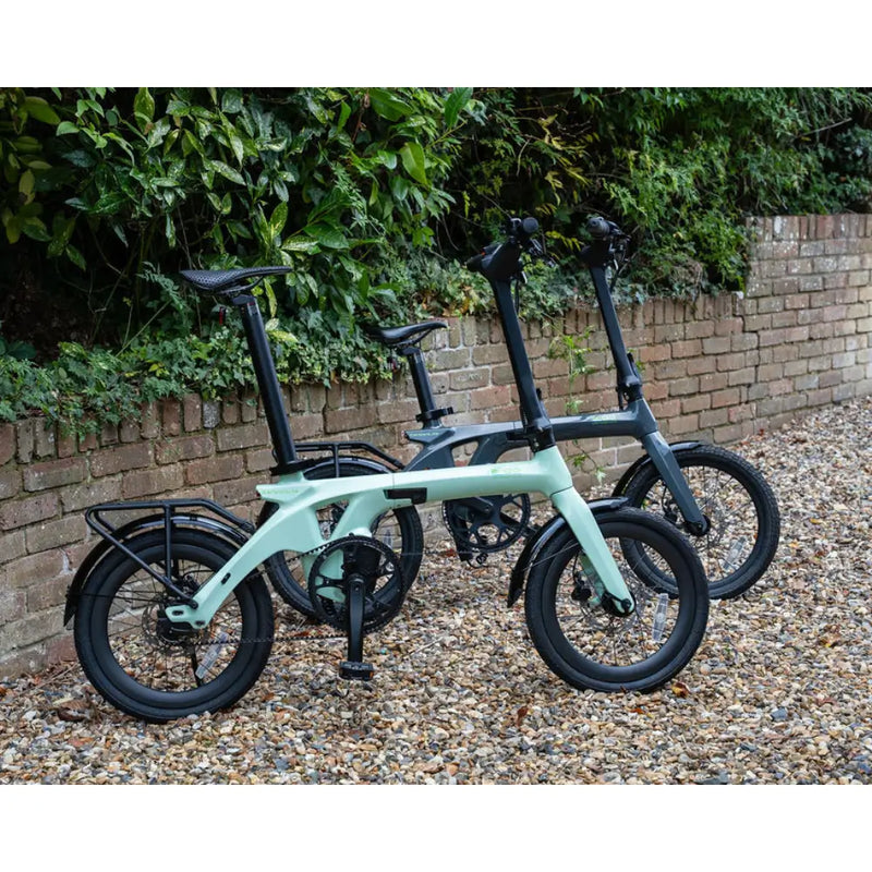 Comparison shot of two E-Go CarbonLite 250W mid-drive folding e-bikes, showing both color options.
