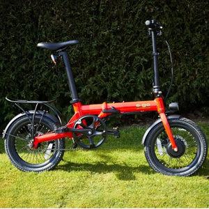Side view of the bright red E-Go Lite folding e-bike on a grassy lawn, highlighting its compact geometry and 250W motor hidden in the front hub.