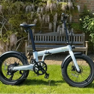 Mint green E-Go Max+ folding electric bike parked on a sunny lawn, highlighting its robust aluminium frame and 20-inch alloy wheels suitable for outdoor leisure.