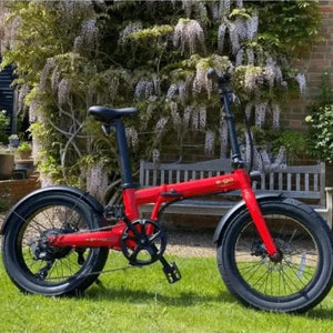 Gloss red E-Go Max+ folding electric bike parked on a sunny lawn, highlighting its robust aluminium frame and 20-inch alloy wheels suitable for outdoor leisure.