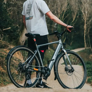 A man holding the right handlebar of an Emu Evo crossbar electric bike, with the backdrop of a forest in winter.