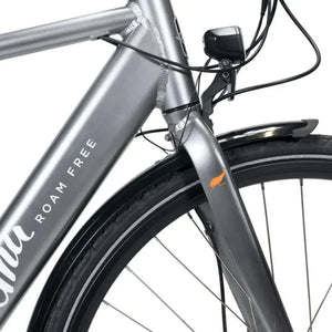 Detail shot of the front suspension fork, integrated front light, and Emu logo on the silver electric bike.
