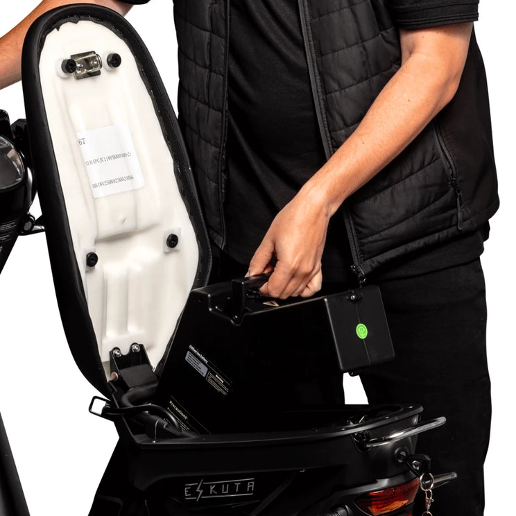 Rider lifting the removable 48V 26Ah battery out from under the seat of the Eskuta SX-250