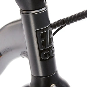 Front view of the embossed EZEGO logo badge on the headtube of the grey Fold Low Step electric bike frame.