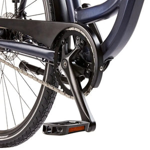 Detail view of the black crankset, pedals, and protective chain guard on the EZEGO Step NX.