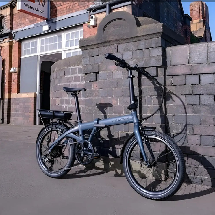 Falcon Compact electric folding bike 250W parked on a UK street near brick buildings, showing commuter-friendly design and compact frame.
