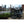 Folded Falcon Compact electric folding bike parked outdoors in an urban setting with city buildings in the background.