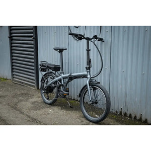 Side view of the Falcon Compact Electric Folding Bike 250W parked beside a brick wall.