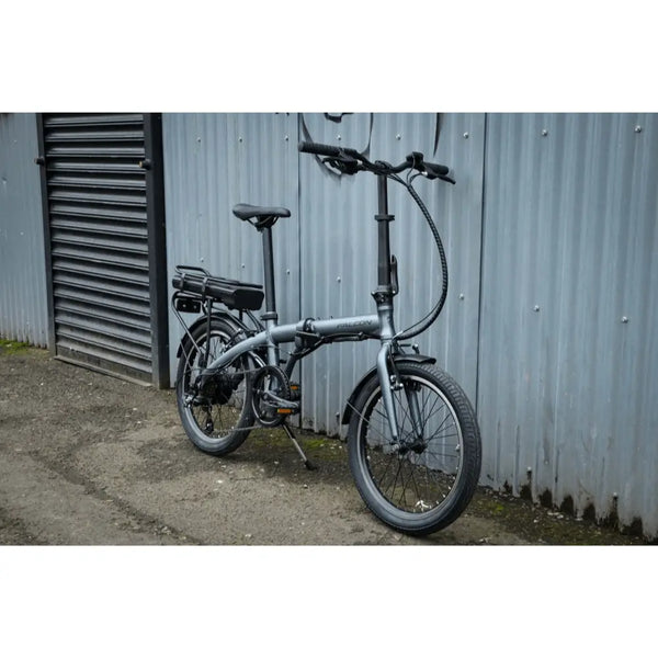 Side view of the Falcon Compact Electric Folding Bike 250W parked beside a brick wall.