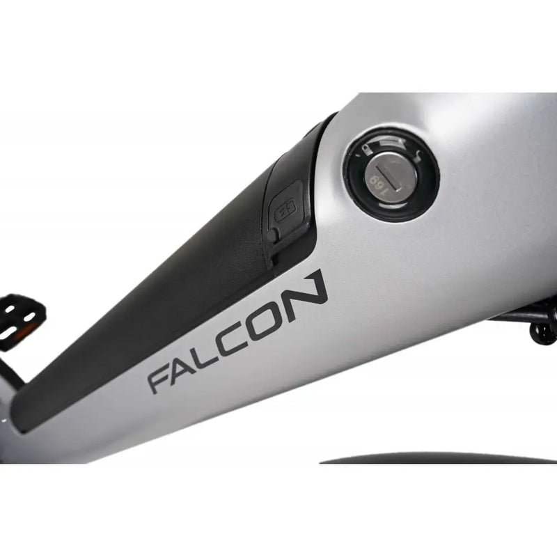 Close-up of the integrated battery compartment on the Falcon Horizon Crossbar electric hybrid bike, highlighting the "FALCON" branding, weather-sealed charging port, and security key lock on the silver downtube.