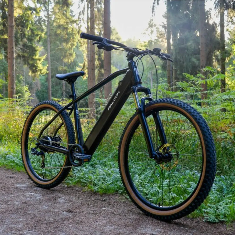 Front angled view of the Falcon Turbine electric mountain bike highlighting the 27.5-inch wheels with tan wall tires and integrated frame battery.