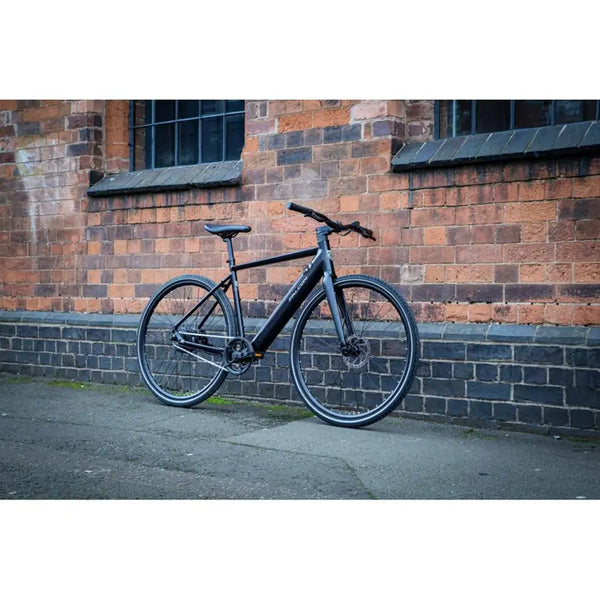 Falcon Zone Single Speed electric hybrid bike parked outdoors against a brick wall, showcasing its sleek and modern design.