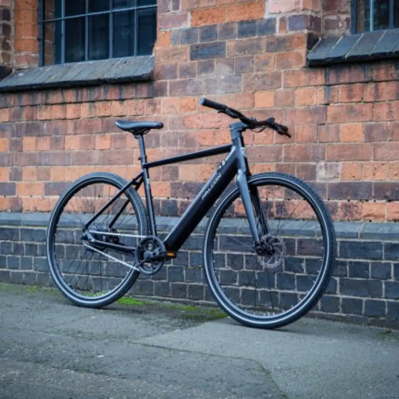 Falcon Zone Single Speed electric hybrid bike parked outdoors against a brick wall, showcasing its sleek and modern design.