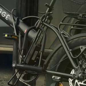 Detailed shot of a Hygge D-lock and security cable fastening a black electric bike frame to a metal post.