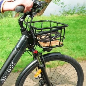 Close-up of the Hygge front basket featuring a stylish wooden base and matte black metal frame mounted on the handlebars of an electric bike.