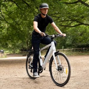 Rider cycling the Hygge Lossø Commuter Hybrid Electric Bike 250W on a forest path surrounded by trees.