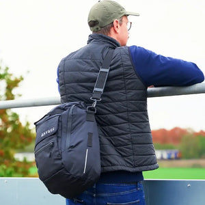 A commuter carrying the black Hygge pannier bag using the detachable shoulder strap, showcasing its versatility as a messenger bag when off the bike.