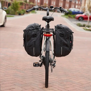 Rear view of a bicycle equipped with two black Hygge pannier bags mounted on either side of the carrier rack, demonstrating the full storage capacity for touring or heavy commuting.