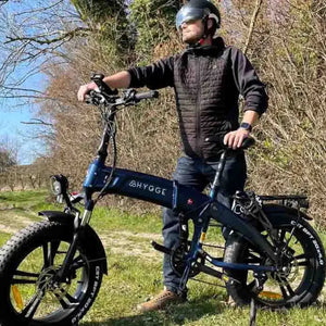 Adult rider standing beside the Hygge Sorø Fat Tyre Folding Electric Bike on an outdoor trail in a natural setting