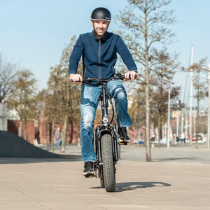 Man riding Hygge Vester folding fat tyre electric bike on an urban path, showcasing stability and comfortable riding position.