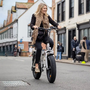 Woman riding Hygge Vester folding electric bike on a city street, ideal for urban commuting with fat tyre stability.