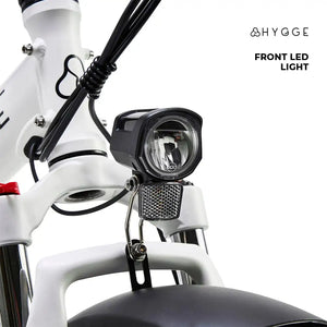 Close-up of the bright LED headlight and front suspension fork on the white Hygge Vester 2025 electric bike.
