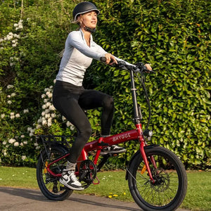 Female rider cycling the Hygge Virum Folding Electric Bike on a paved path surrounded by greenery.