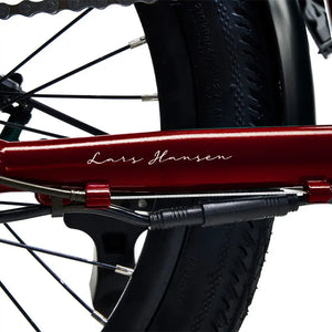 Close-up of the 'Lars Hansen' signature on the red frame, highlighting the bike's Danish design heritage.