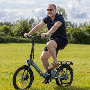 Rider cycling Hygge Virum folding electric bike across open field showing comfort and versatility for everyday use.