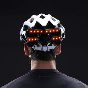 Person wearing a white bicycle helmet with red LED lights on a black background