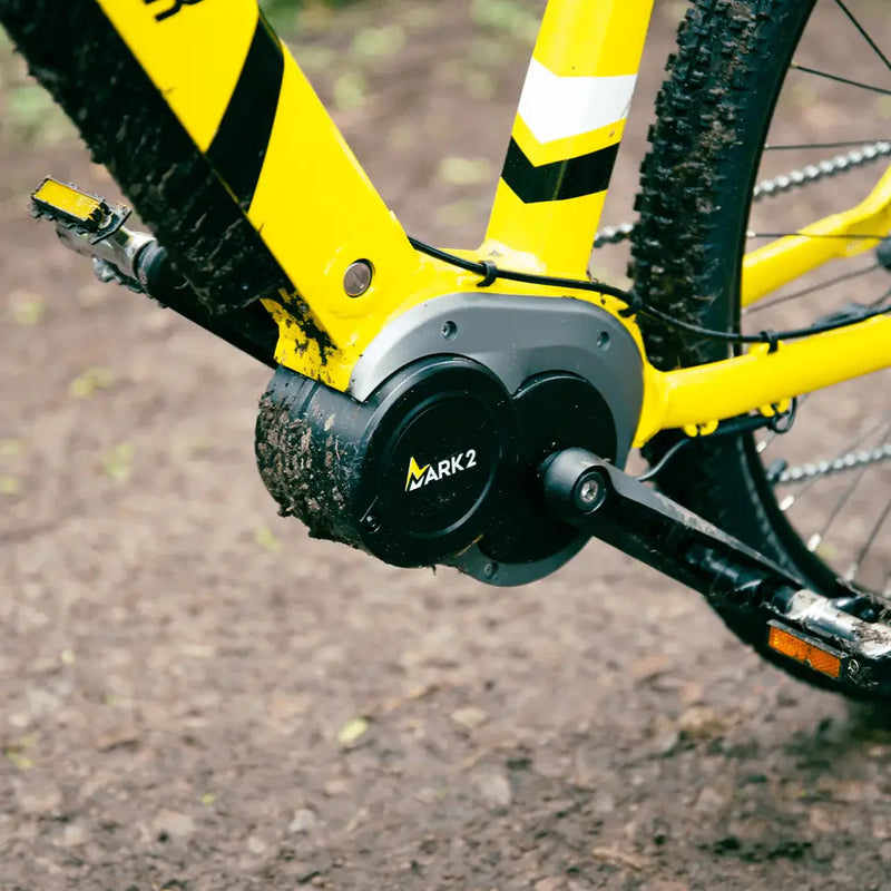 Close-up of the high-torque 250W mid-drive motor on the Mark2 Scrambler, showing its rugged build with mud splashes from off-road riding.