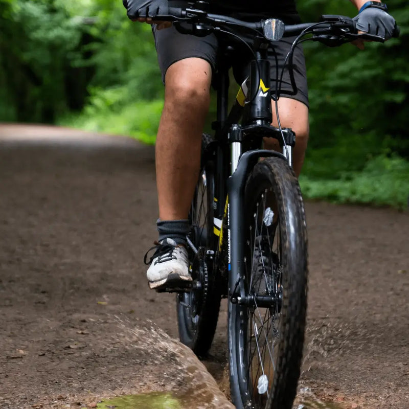 Action shot of the Mark2 Scrambler lightweight electric bike being ridden through a muddy off-road puddle.