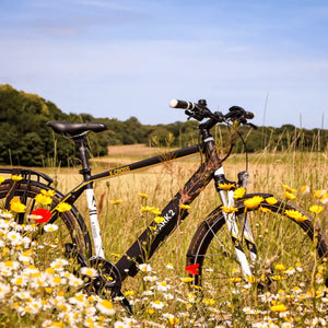 Side profile view of the Mark2 X-Cross 520 hybrid electric bike parked in a meadow of wildflowers.