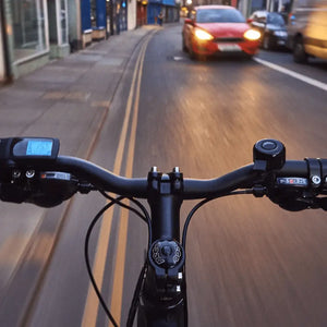 POV shot from the handlebars of the Mark2 X-Cross 520 electric bike riding through a city street at dusk.