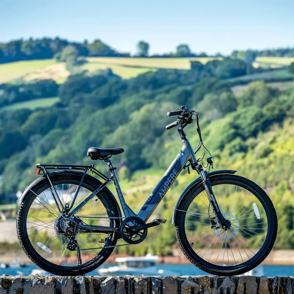 Ampere Deluxe step-through hybrid electric bike positioned outdoors with countryside scenery in the background