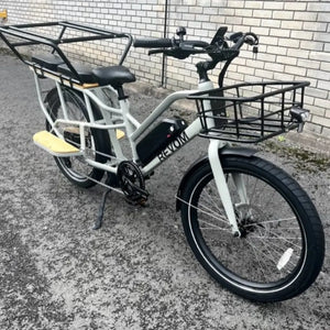 Full side view of the grey Revom ECargo 2.3 electric bike equipped with a full rear passenger safety cage and front basket.