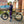 A woman stands next to a light green Revom Multi C2 cargo e-bike with a large rear rack and front basket.