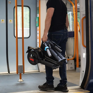 A commuter carrying the lightweight, folded Riley RS3 electric scooter onto a train.