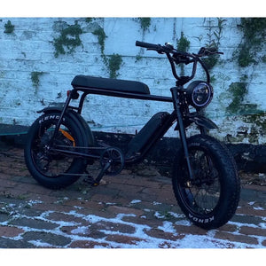 Front left view of the Rocket 88X Fat Boy electric bike with 350W motor, rugged tyres, and integrated LED headlight, parked on cobbled ground.