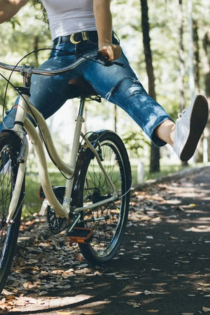 Person riding a bicycle on a leaf-covered path in a park